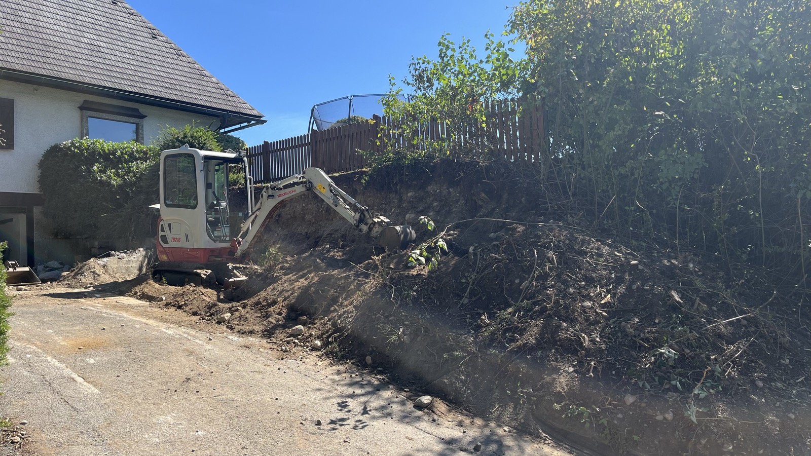 Minibagger bei Aushubarbeiten neben Wohnhaus