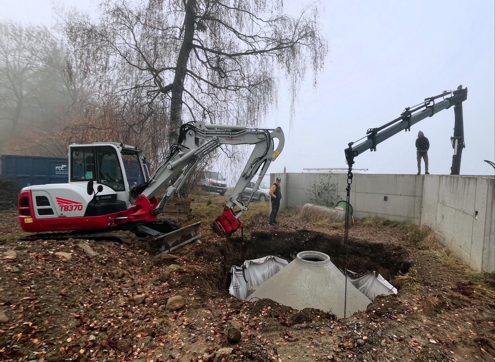 Bagger beim Setzen eines Kanalschachts